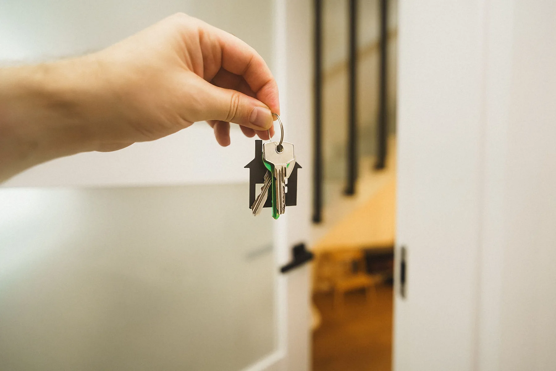 Hand mit Wohnungsschlüsseln in einem hellen Wohnraum